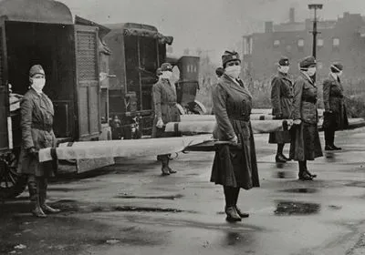 Photograph from 1918 influenza pandemic shows mask-wearing women holding stretchers at backs of ambulances in Saint Louis, Missouri. Photograph from 1918 influenza pandemic shows mask-wearing women holding stretchers at backs of ambulances in Saint Louis, Missouri.